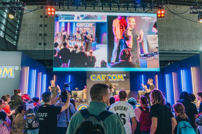 Photo de la finale de la CapGame Arena sur la scène Capcom.
Deux joueurs sont entrain de s'affronter sur le jeux vidéo de combat.
Sur la scène il y a deux commentateurs et un interprète en langue des signes française.
