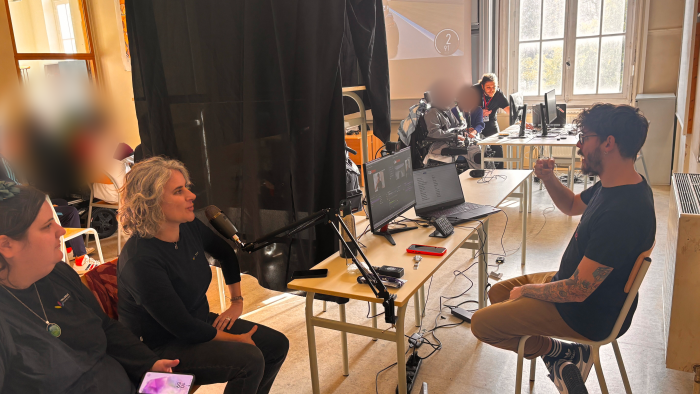 Sur la photo, il y a le commentateur de la CapGame Arena en train de parler en langue des signes française. Les interprètes parlent dans le micro pour le live twitch. Dans le fond de la pièce, nous pouvons voir l'un des joueurs sur le jeux Forza Motorsport.