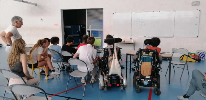 Une dizaine de personnes est assise en train de regarder les deux équipes s'affronter sur Efootball.