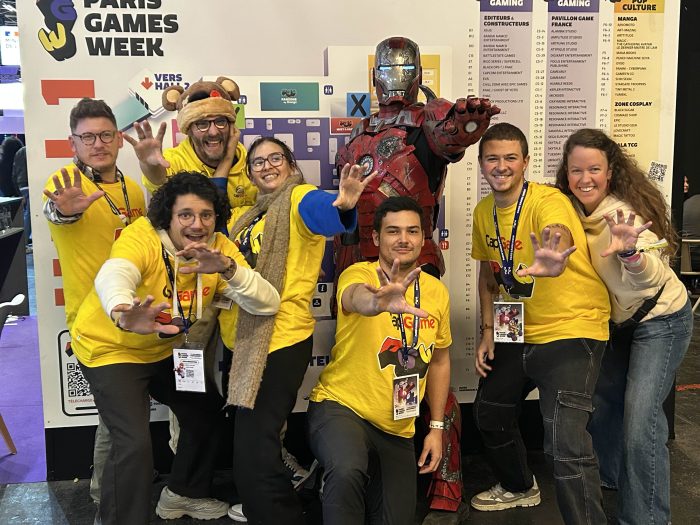 7 membres de l'équipe access avec Iron Man, dans la posture typique du héros, un bras tendu et paume de la main vers l'avant (plan de la PGW en arrière plan)